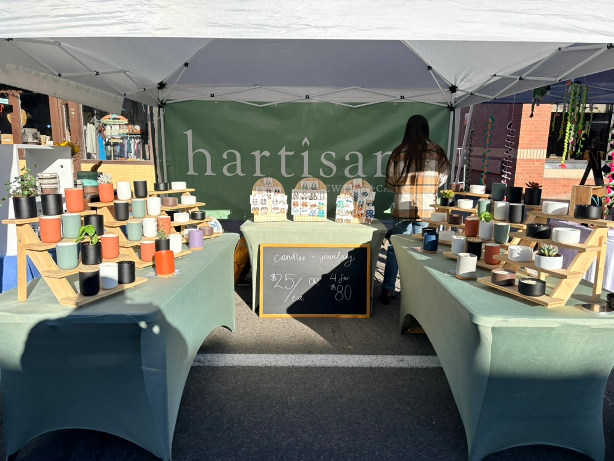 Hartisans Durango candles at a local market, unlabeled ceramic jars on sage tables