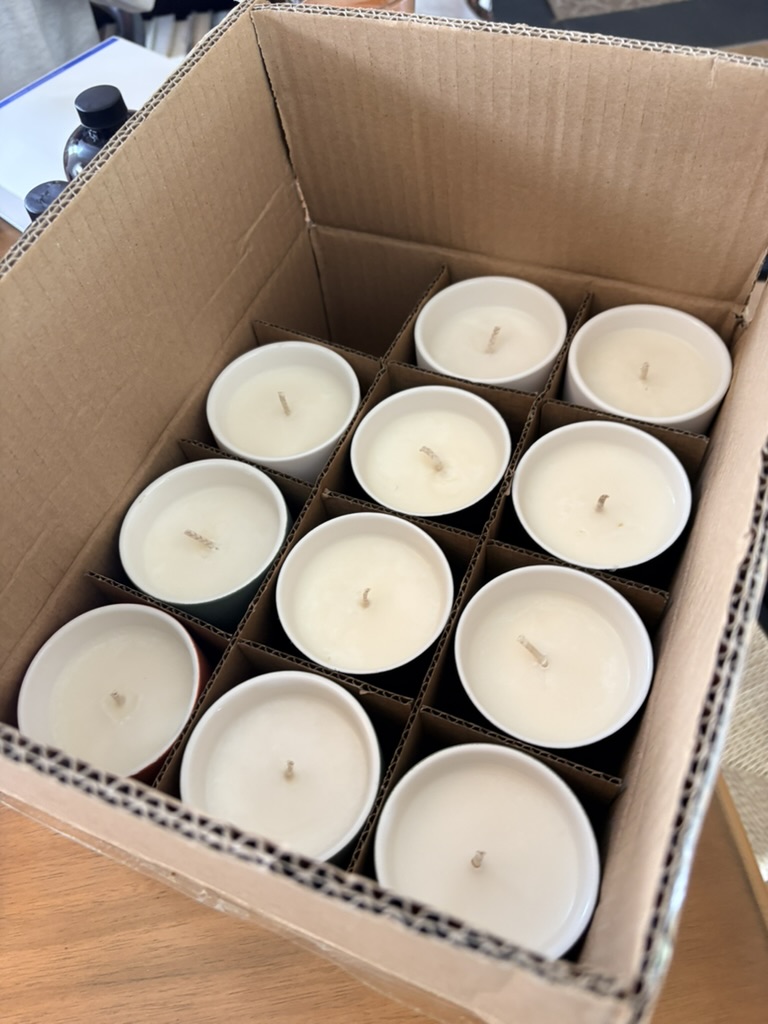 Eleven white candles packed in a cardboard divider box
